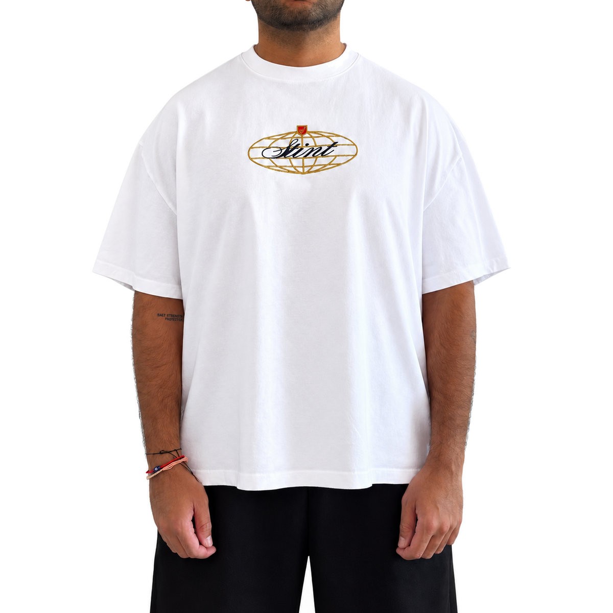 962 Tee by STINT GEAR worn front view. Blue, gold, and red on white. Model wears size XL.