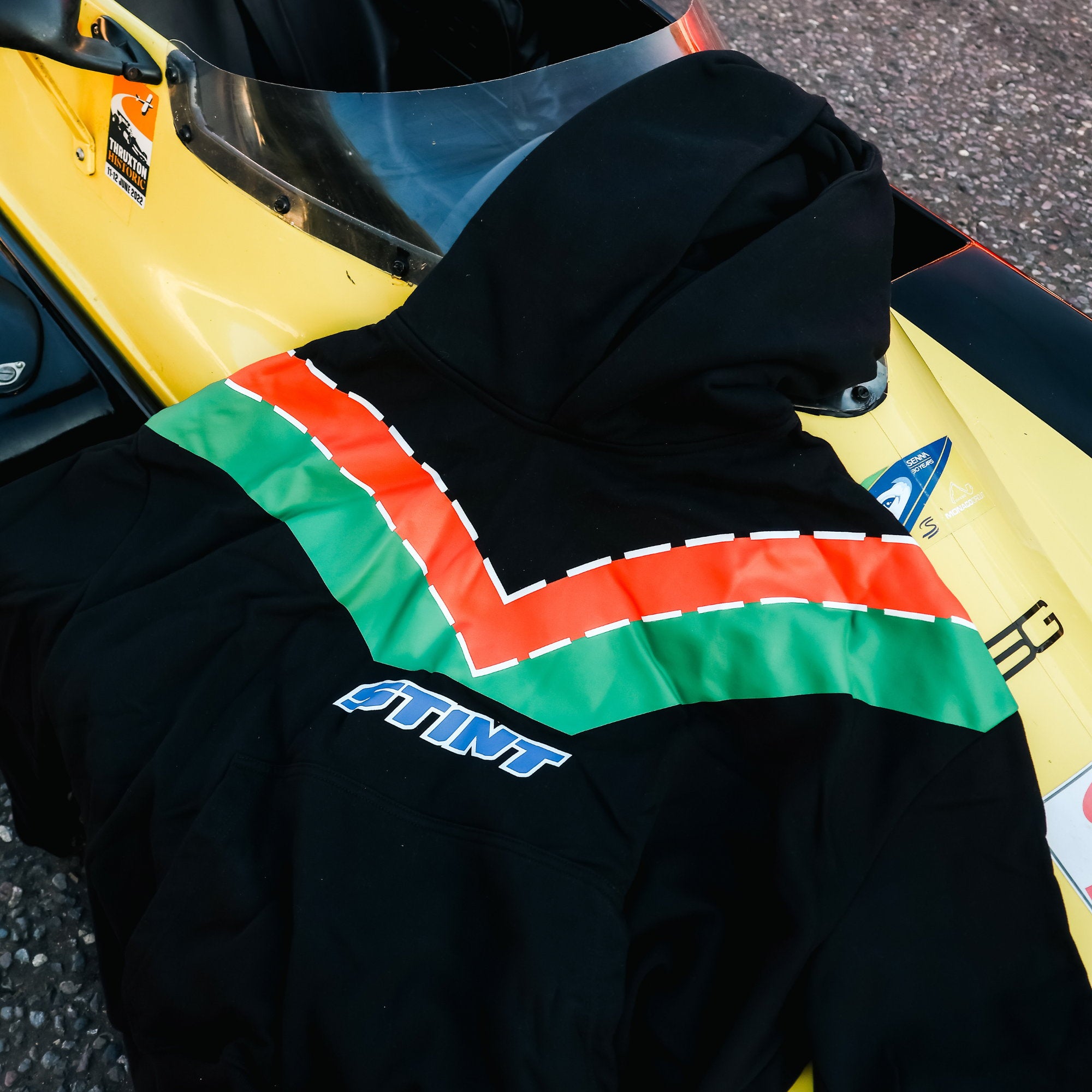 Rotary Hoodie by STINT GEAR. Orange and green 787B livery on black, on a single-seater race car. Motorsport livery apparel.